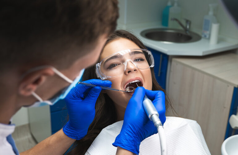 Dentist performing root canal treatment on a patient using dental instruments and protective eyewear